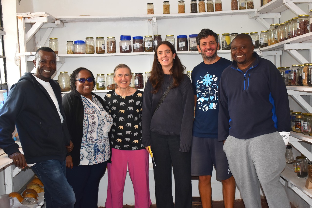 IATP and friends in front of a wall of saved seeds and grains