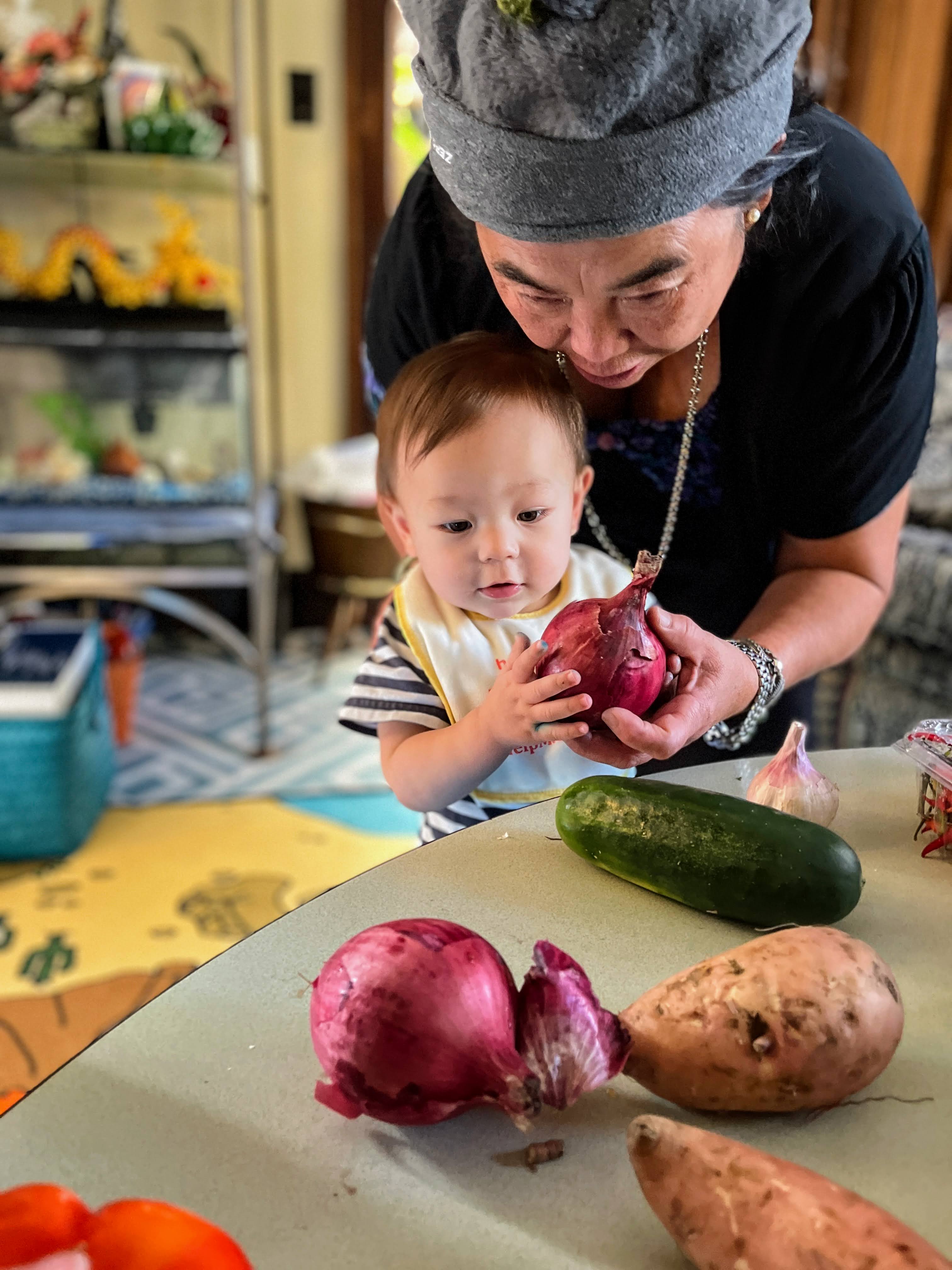 Early care provider Souvanh Thao shows HAFA CSA vegetables to a child