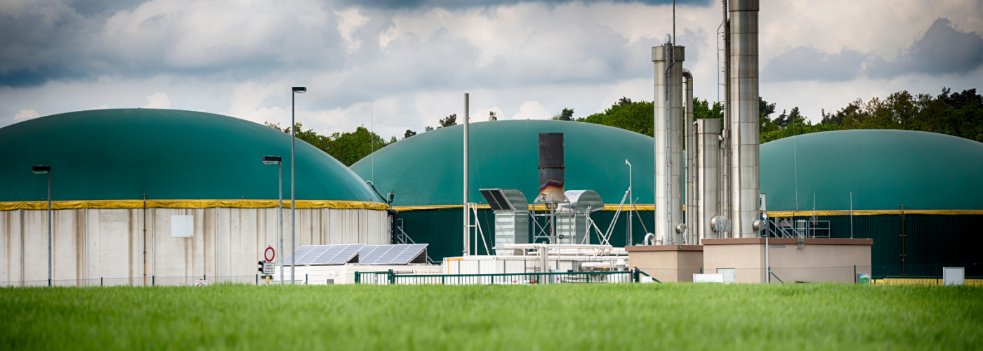 Large green domes of biogas digesters under cloudy sky