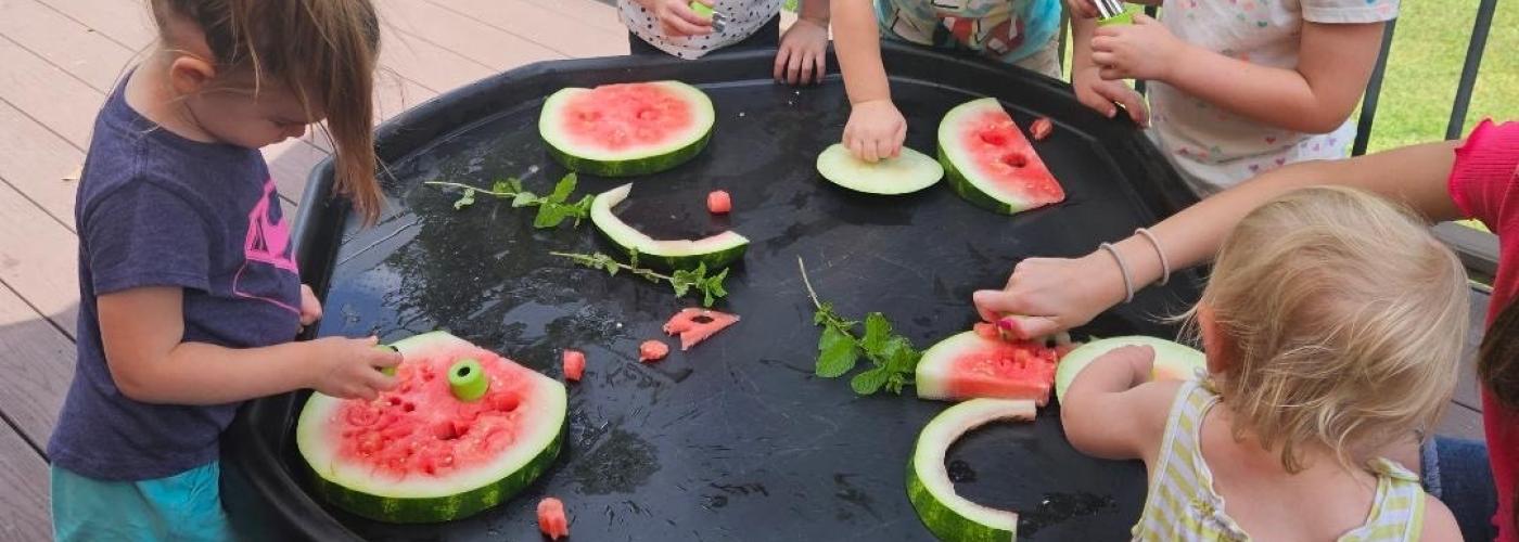 Children in early care explore watermelon slices