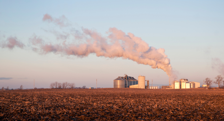Image of an ethanol plant smokestack next to a corn field