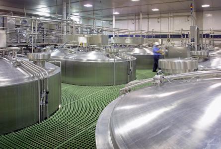 inspector walking past food storage tanks.