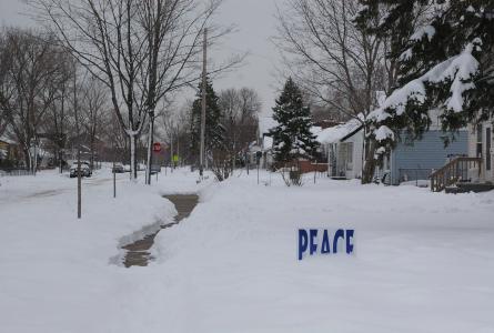 Snowy Minneapolis neighborhood with "Peace" sign in yard. Photo by Taylor Dahlin.